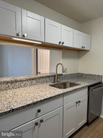 a kitchen with granite countertop white cabinets and a sink