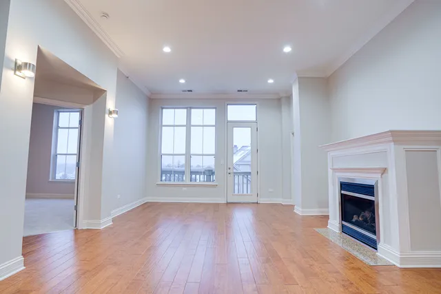 a view of an empty room with wooden floor and a fireplace