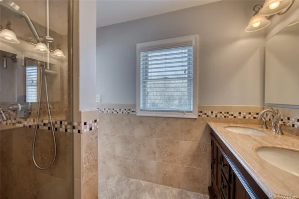 a bathroom with a granite countertop shower a sink and a mirror