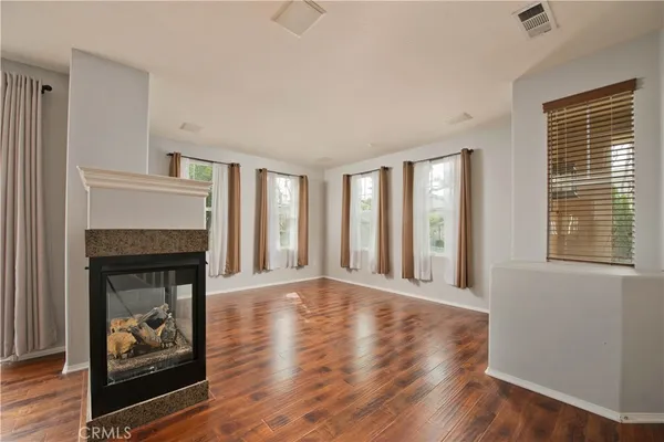 a view of an empty room with wooden floor fireplace and a window
