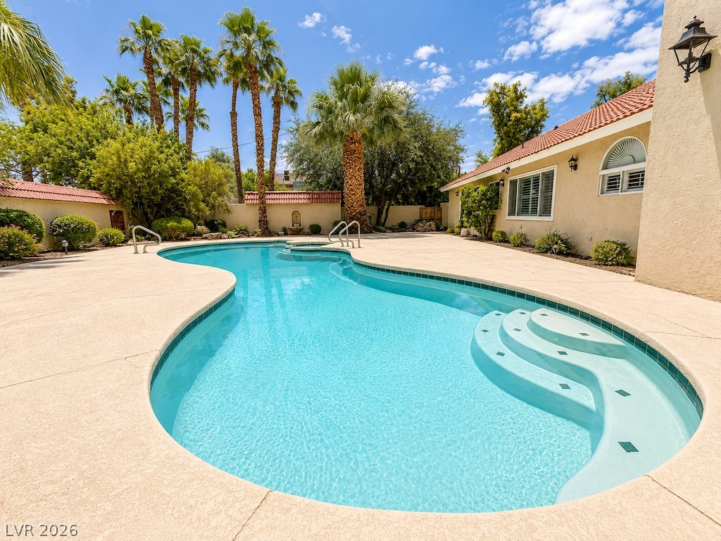 3010 East Viking Road Las Vegas, NV 89121 - Photo 43 of 48 An inviting backyard oasis offers a pristine pool with integrated steps, surrounded by generous patio space and lush landscaping.