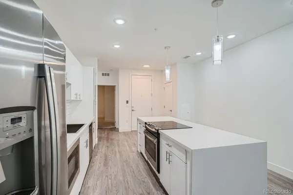 a kitchen with a stove a refrigerator a sink and white cabinets with wooden floor