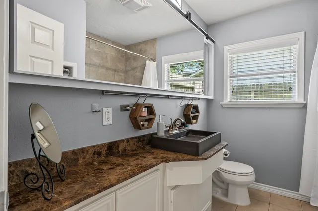 a bathroom with a granite countertop sink a toilet and a window