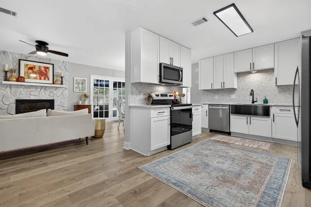a kitchen with granite countertop a refrigerator oven a sink and white cabinets