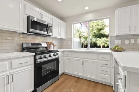 a kitchen with stainless steel appliances white cabinets granite counter tops and a window