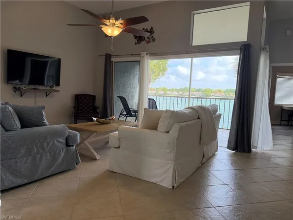 a living room with furniture a flat screen tv and a large window
