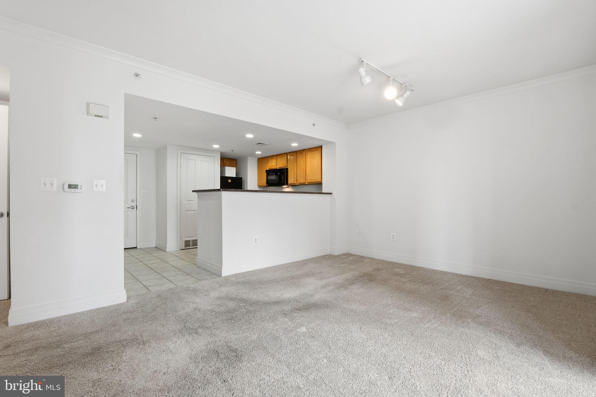 414 Water Street, Unit 1304 Baltimore, MD 21202 - Photo 2 of 24 an empty room with a kitchen and a chandelier fan