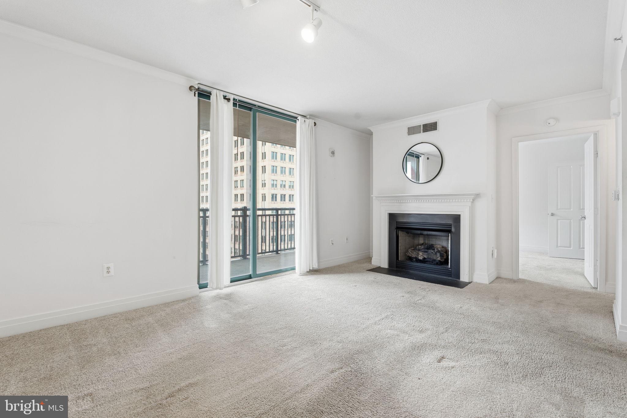 414 Water Street, Unit 1304 Baltimore, MD 21202 - Photo 4 of 24 a view of an empty room with a fireplace and a window
