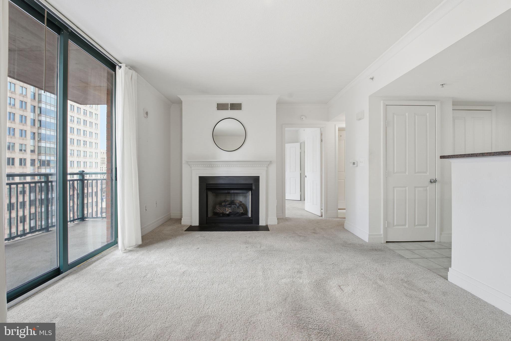 414 Water Street, Unit 1304 Baltimore, MD 21202 - Photo 6 of 24 a view of an empty room with a fireplace and a window
