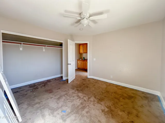 an empty room with closet and a ceiling fan