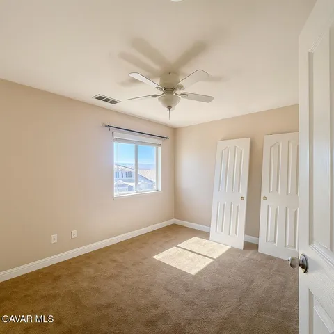 an empty room with a ceiling fan and window