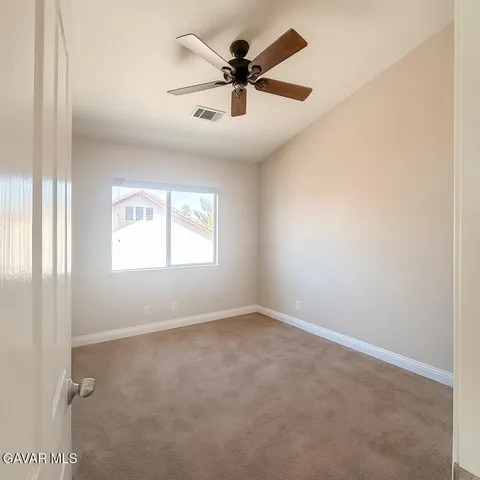 an empty room with windows and ceiling fan