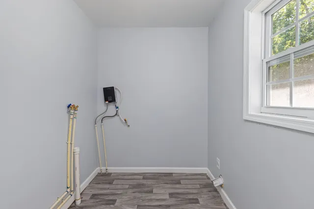 an empty room with wooden floor cabinet and windows