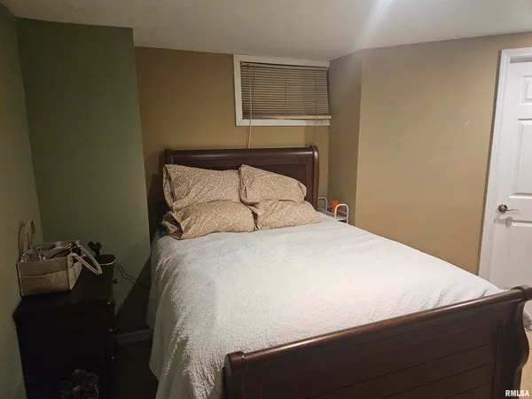 a large bed sitting in a bedroom next to a window and a wooden chair