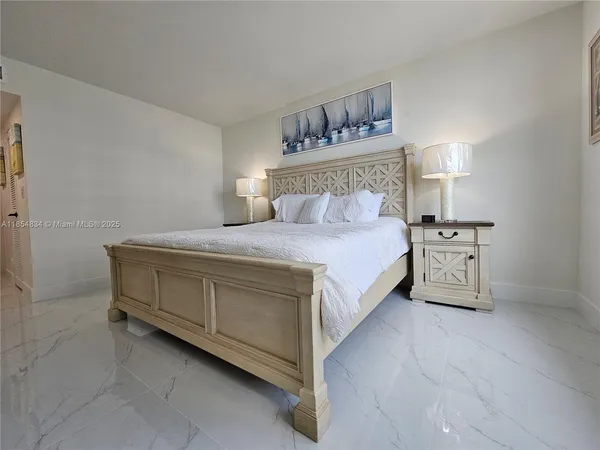 a spacious bedroom with a bed and a lamp on the dresser