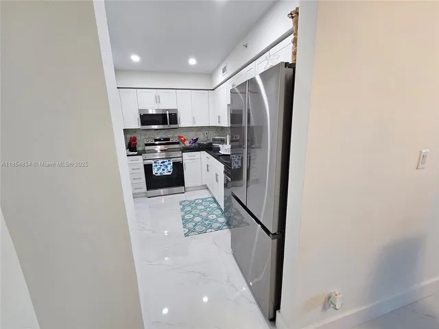 a kitchen with stainless steel appliances granite countertop a refrigerator and a sink