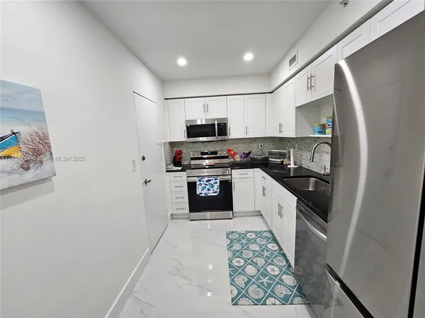 a kitchen with granite countertop a refrigerator stove and sink