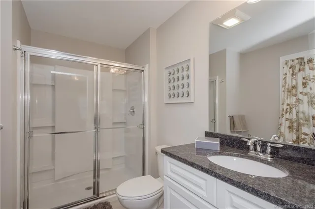 a bathroom with a granite countertop sink toilet a mirror and shower