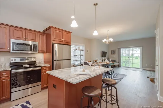 a kitchen with stainless steel appliances granite countertop a stove a refrigerator a sink a dining table and chairs