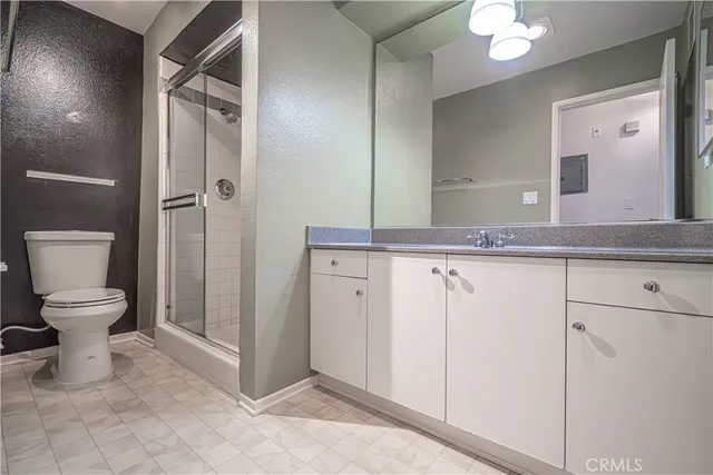 a spacious bathroom with a granite countertop sink toilet a mirror and shower