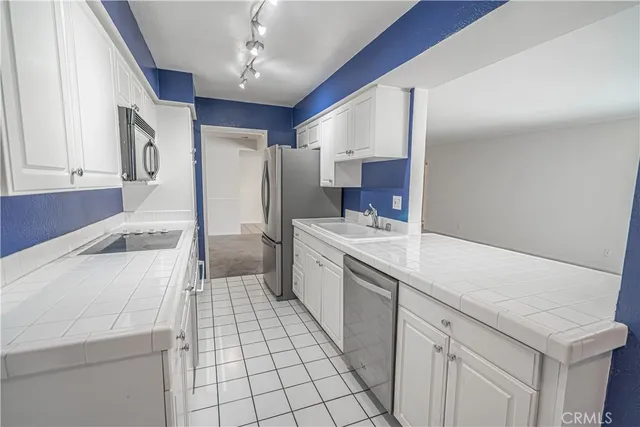 a large white kitchen with a sink and dishwasher a refrigerator with white cabinets