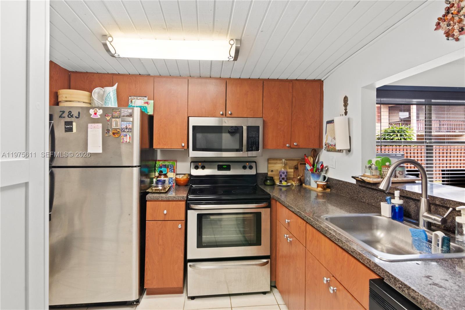 11209 Southwest 88th Street, Unit 101B Miami, FL 33176 - Photo 3 of 28 a kitchen with stainless steel appliances granite countertop a refrigerator a stove a sink and a microwave