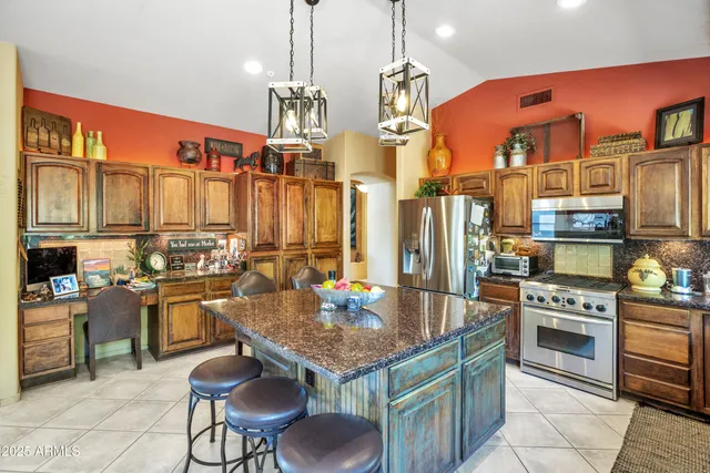a kitchen with stainless steel appliances granite countertop a stove a refrigerator a kitchen island a dining table and chairs with wooden floor