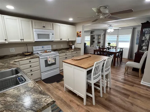 a kitchen with stainless steel appliances granite countertop a stove top oven a sink dishwasher and white cabinets with wooden floor