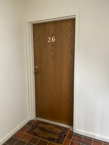 a view of an empty room with wooden floor fireplace and a window