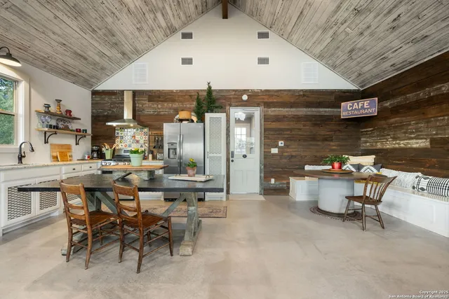 a kitchen with stainless steel appliances granite countertop a dining table chairs refrigerator and sink