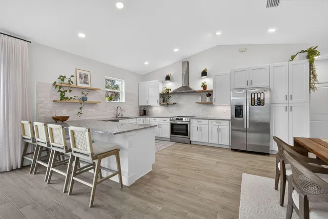a kitchen with stainless steel appliances granite countertop a table chairs sink and cabinets