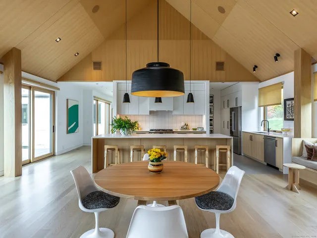 a kitchen with stainless steel appliances granite countertop a stove a sink dishwasher a dining table and chairs with wooden floor