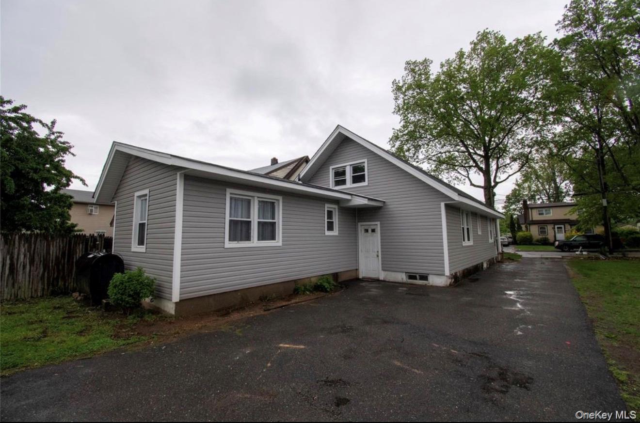 76 Henry Street Roosevelt, NY 11575 - Photo 12 of 14 a front view of house with yard and trees