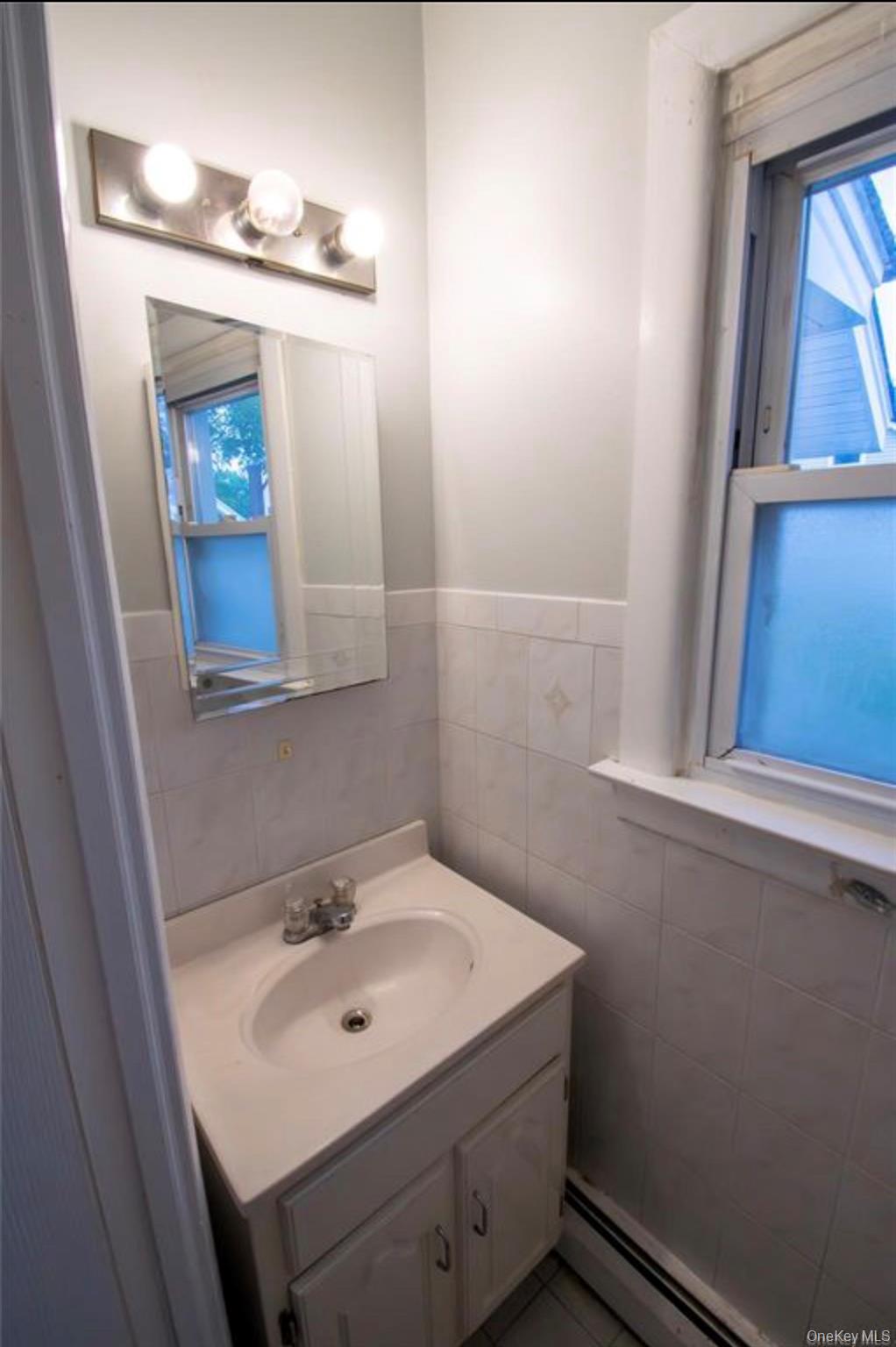 76 Henry Street Roosevelt, NY 11575 - Photo 7 of 14 a bathroom with a sink a mirror and vanity