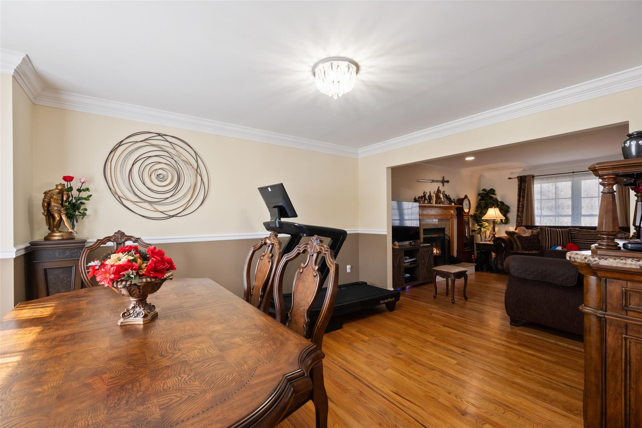 15 Bobrick Road Poughkeepsie, NY 12601 - Photo 10 of 36 Dining room featuring a chandelier, light wood finished floors, a lit fireplace, and crown molding