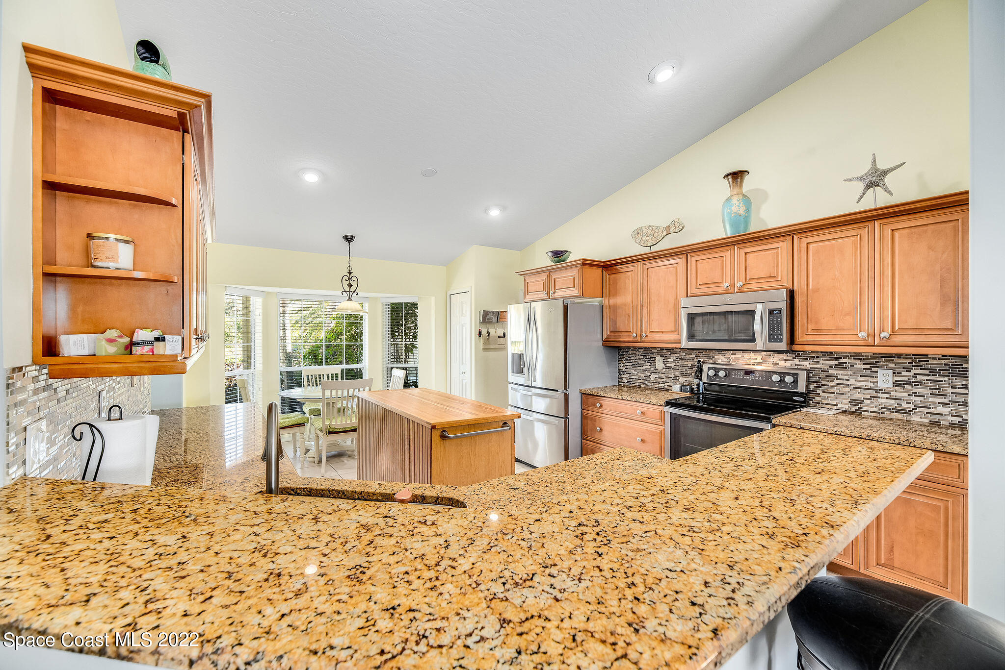 1566 Eagles Circle Sebastian, FL 32958 - Photo 21 of 59 a kitchen with stainless steel appliances kitchen island granite countertop a refrigerator stove oven dining table and chairs with wooden floor