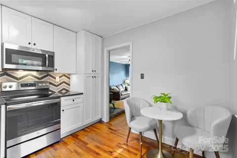 a kitchen with stainless steel appliances kitchen island granite countertop a stove a refrigerator and a dining table with wooden floor