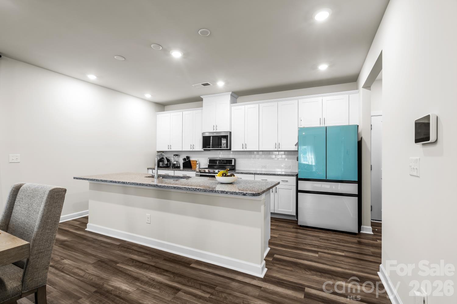 11955 Old Statesville Road Huntersville, NC 28078 - Photo 8 of 20 a kitchen with stainless steel appliances granite countertop a stove a refrigerator a microwave oven with white cabinets and wooden floor