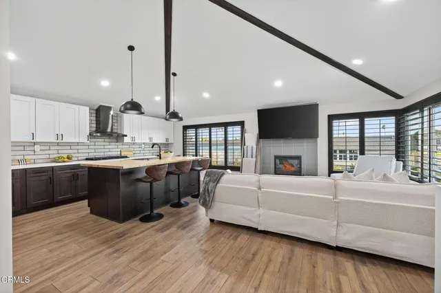 a large kitchen with a large counter top space a sink stainless steel appliances and living room view