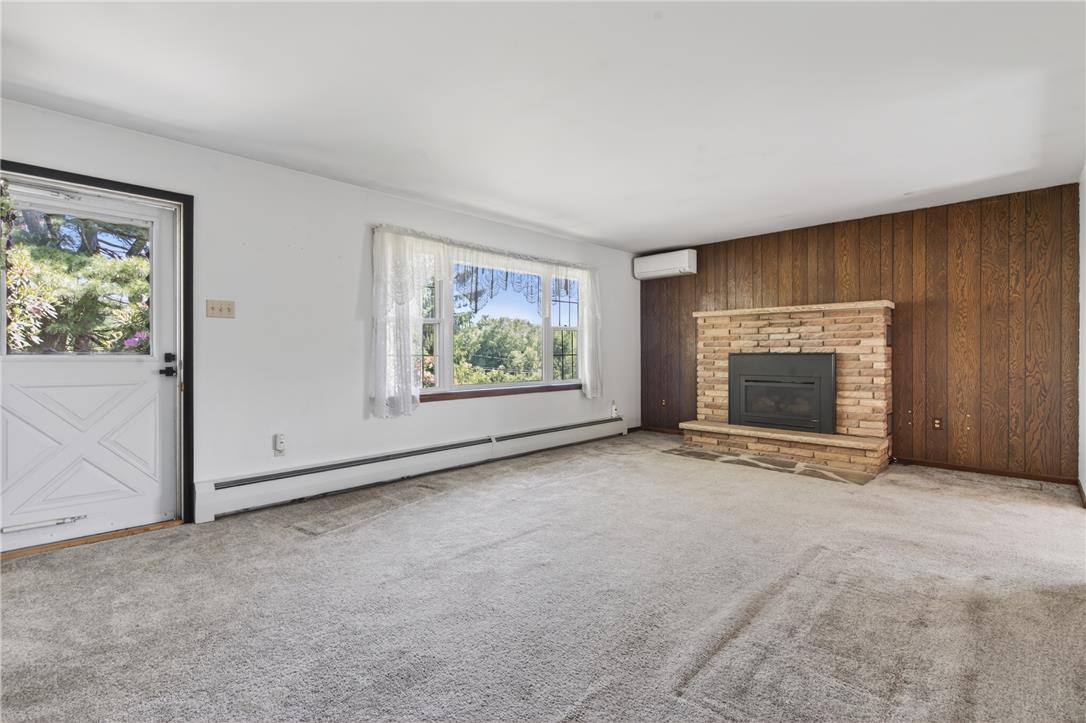 62 Stoney Road Tamaqua, PA 18252 - Photo 8 of 61 A spacious living room with a rustic stone fireplace and wood-paneled accent wall.