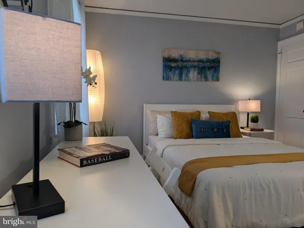 a bedroom with a bed a lamp and a potted plant