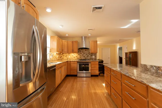 a large kitchen with kitchen island granite countertop a large counter top stainless steel appliances and cabinets