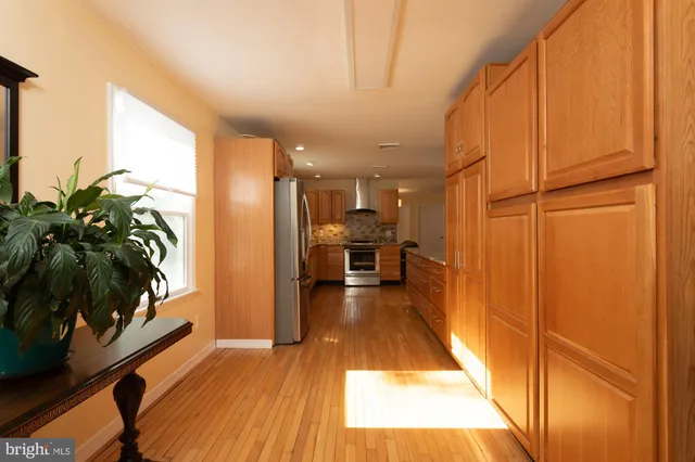 a view of a hallway with wooden floor and a kitchen