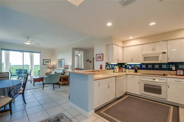 a large white kitchen with chairs stove and sink