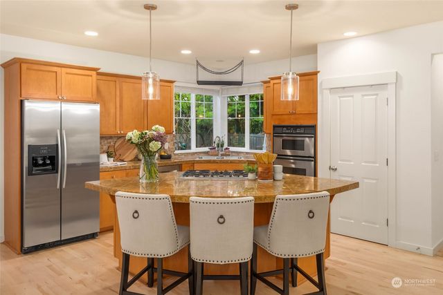 a kitchen with stainless steel appliances granite countertop a table chairs and a refrigerator