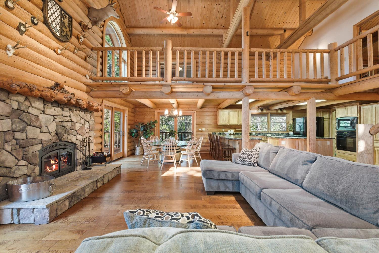 2428 Rancho Paradiso Arnold, CA 95223 - Photo 3 of 67 Soaring vaulted great room with exposed timber trusses, arched picture windows, and a grand stone-surround fireplace with a rustic mantel.