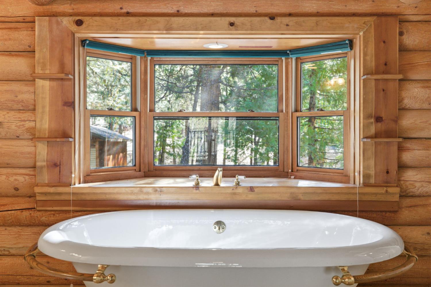 2428 Rancho Paradiso Arnold, CA 95223 - Photo 40 of 67 A private guest suite features a stunning clawfoot soaking tub framed by full log walls and a forest-view window, making it the kind of guest room people never want to leave.