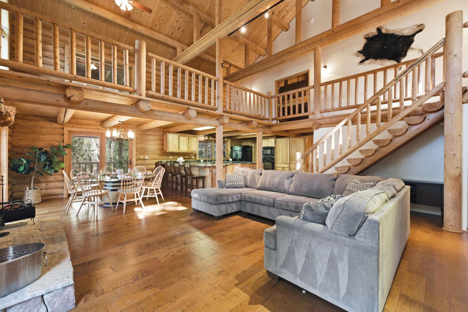2428 Rancho Paradiso Arnold, CA 95223 - Photo 4 of 67 Soaring vaulted great room with exposed timber trusses, arched picture windows, and a grand stone-surround fireplace with a rustic mantel.