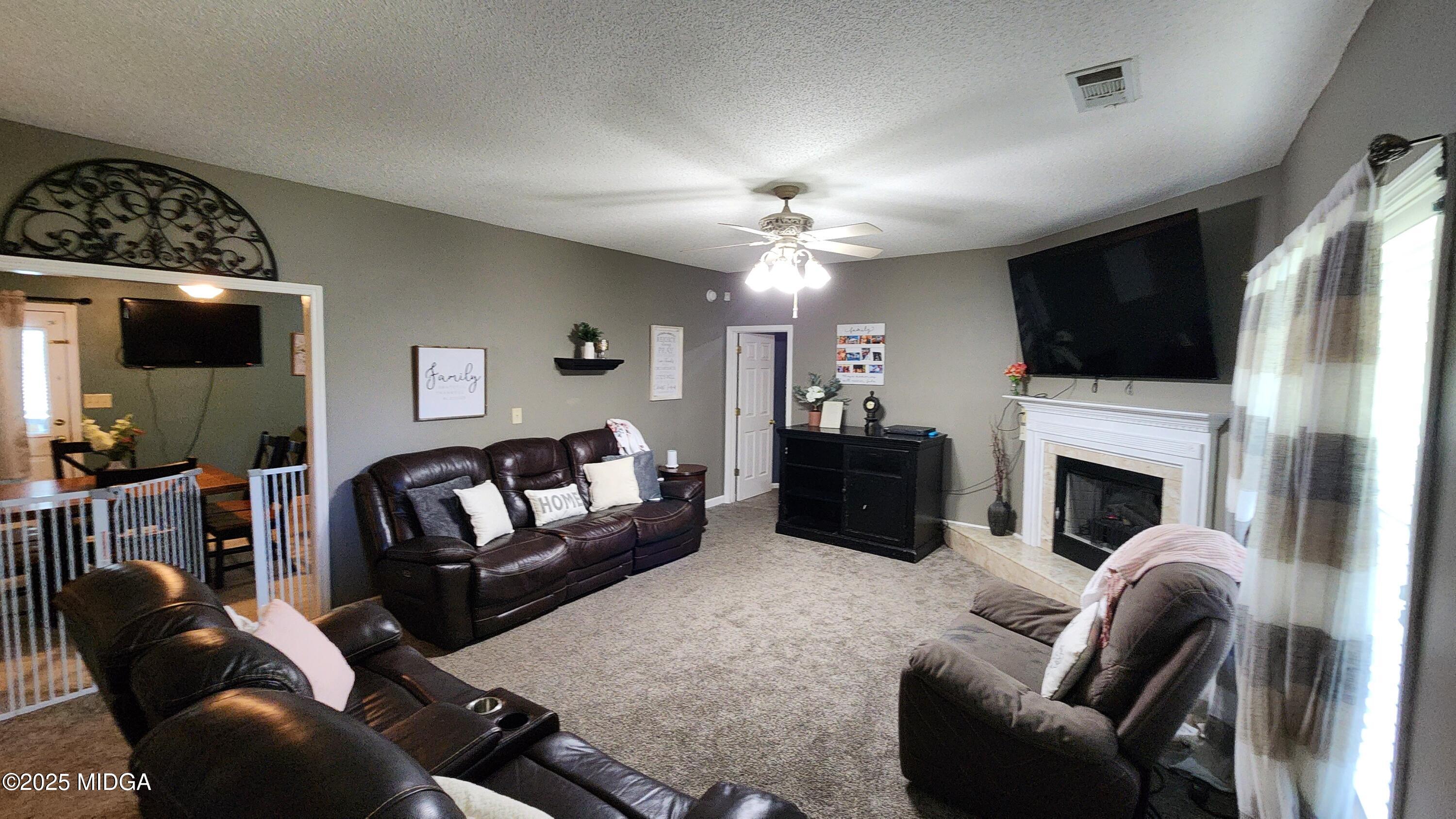 702 Carl Sutton Road Lizella, GA 31052 - Photo 4 of 43 a living room with furniture a fireplace and a flat screen tv