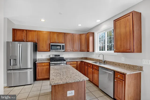 a kitchen with stainless steel appliances granite countertop a sink stove microwave and refrigerator